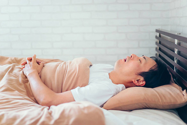 口を開けてベッドに横たわる男性