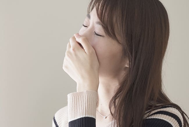 げっぷを抑える女性