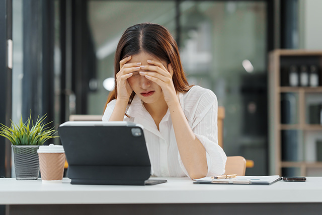 デスクワーク中に眠そうに頭を抱えている会社員女性